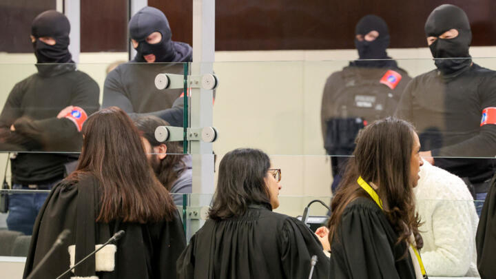 Defence lawyers talk to defendants through a specially designed glass box in the courtroom before the start of the trial of alleged jihadists accused of directing or aiding suicide bombings in Brussels on March 22, 2016, at the Justitia building in Brussels, December 5, 2022.